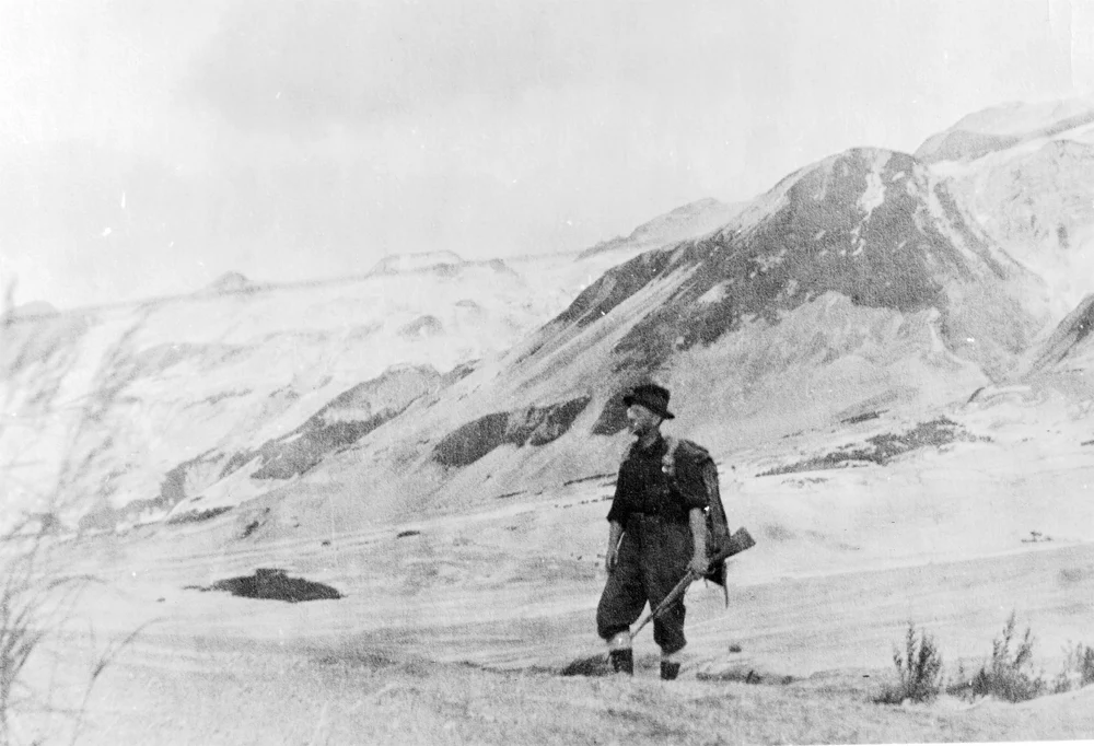 Black and white photo of hunter scouting a snowy, mountainous landscape