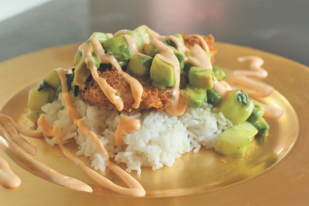 Display of panko halibut served with cucumber avocado relish and spicy mayo sauce on bed of rice