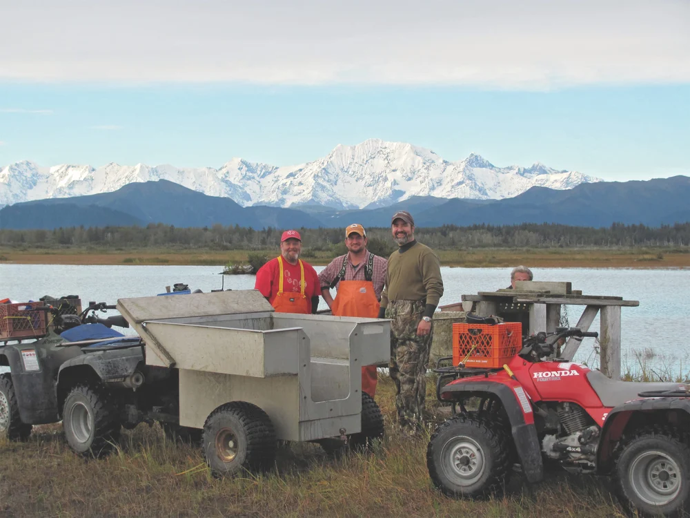 Three fishermen posing in front of river and mountains